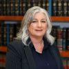 Tammy McClenney in a suit poses confidently in a library with legal books. Business, expertise, and elegance.