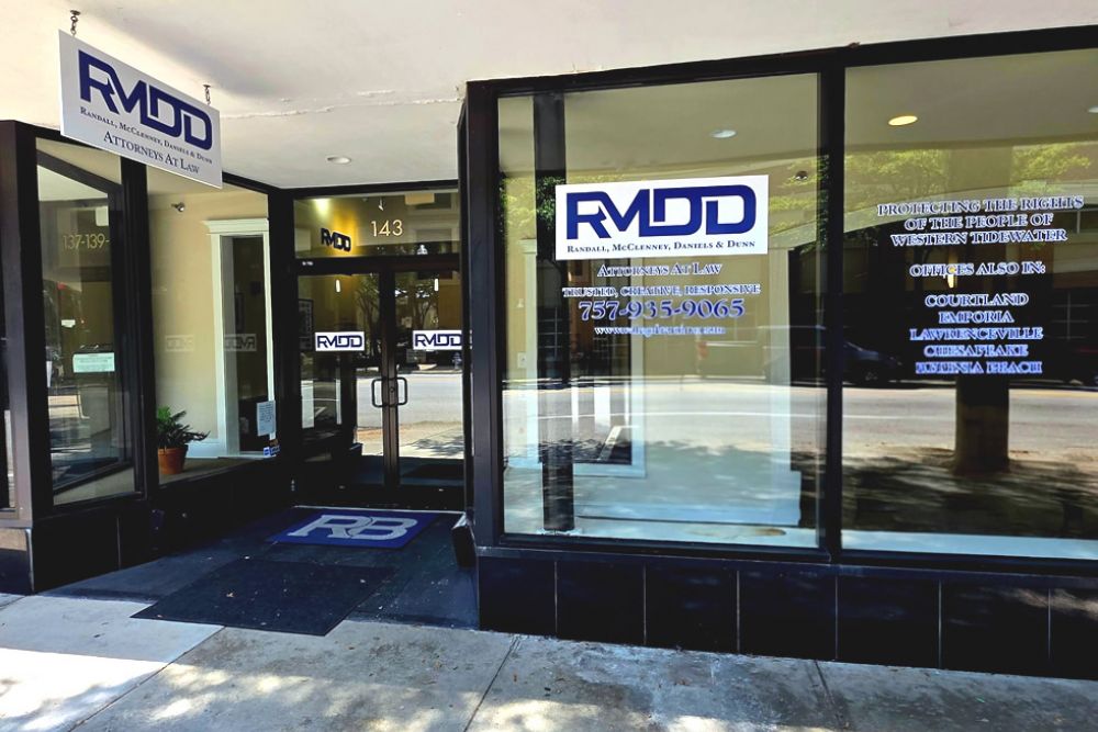 Front of law firm office RMDD, glass windows, signage with phone number and website, sunny street view.